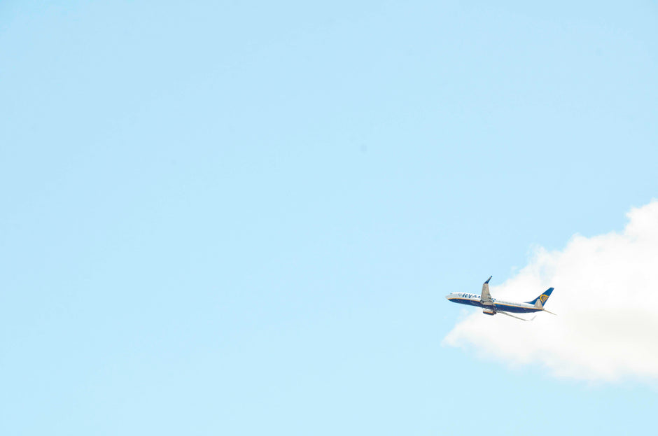 plane ascending against a blue sky with a white cloud