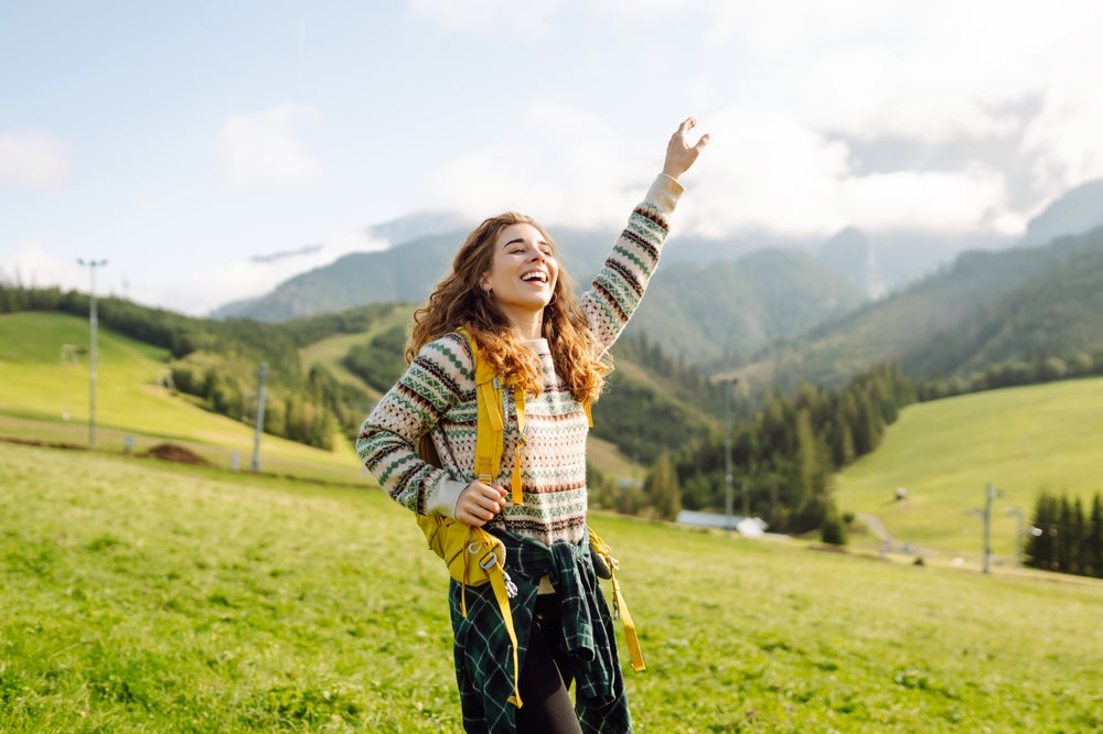 Woman standing in a grassy field with mountains in the background