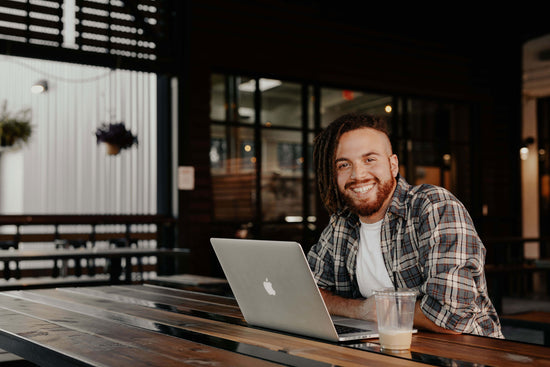 Man sitting at a table with a laptop working on the 100-hour OISE TEFL course